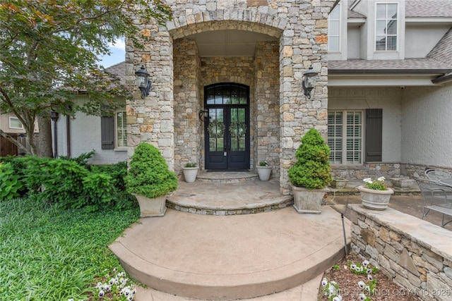 4620 E 108th Pl S, Tulsa, OK 74137 - view of exterior entry featuring french doors, stone siding, stucco siding, and a shingled roof