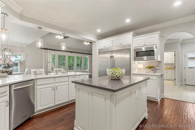 4620 E 108th Pl S, Tulsa, OK 74137 - kitchen featuring built in appliances, a center island, white cabinetry, decorative backsplash, and ornamental molding