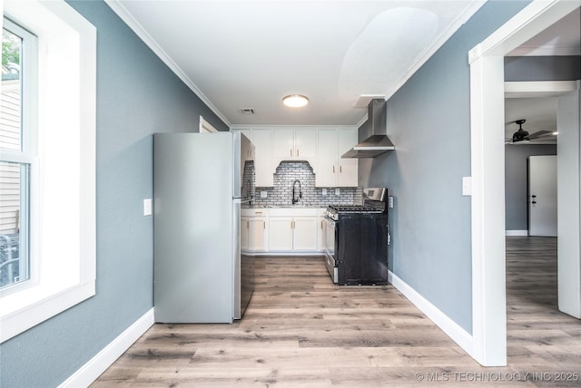 2532 E 4th St, Tulsa, OK 74104 - kitchen featuring stainless steel appliances, wall chimney range hood, white cabinets, backsplash, and crown molding