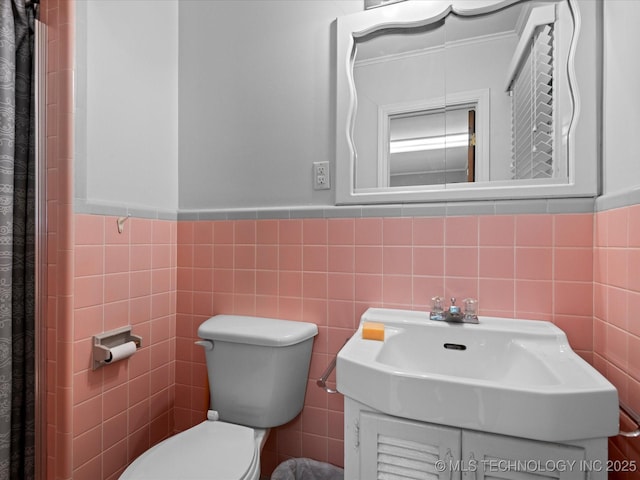 320 E 7th St, Pawhuska, OK 74056 - full bathroom featuring tile walls, a wainscoted wall, vanity, and a shower with shower curtain