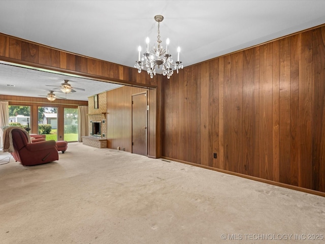 320 E 7th St, Pawhuska, OK 74056 - unfurnished living room featuring wooden walls, carpet, a chandelier, a ceiling fan, and a fireplace