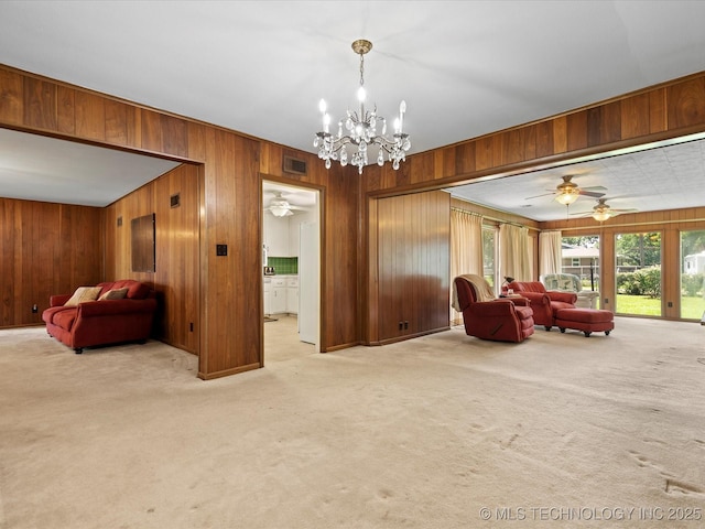 320 E 7th St, Pawhuska, OK 74056 - living room with wood walls, carpet, a chandelier, and ceiling fan