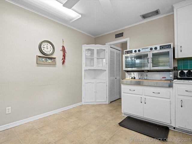 320 E 7th St, Pawhuska, OK 74056 - kitchen featuring white cabinetry, ornamental molding, light countertops, and tasteful backsplash