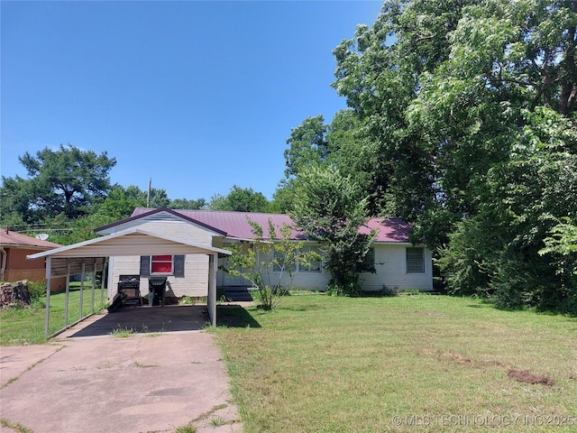 1713 E 10th St, Okmulgee, OK 74447 - view of front of home with driveway, a front yard, a metal roof, and a carport