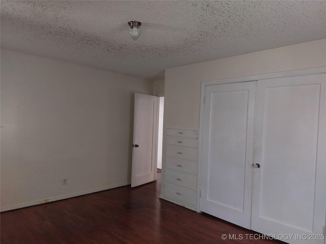 1713 E 10th St, Okmulgee, OK 74447 - unfurnished bedroom with wood finished floors, a textured ceiling, and a closet