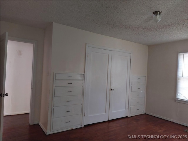 1713 E 10th St, Okmulgee, OK 74447 - unfurnished bedroom featuring dark wood-style floors, a textured ceiling, and a closet