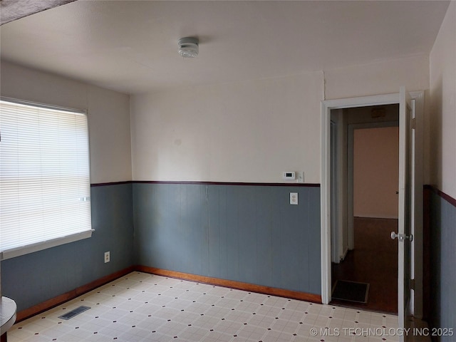 1713 E 10th St, Okmulgee, OK 74447 - empty room with tile patterned floors, a smoke detector, and a wainscoted wall