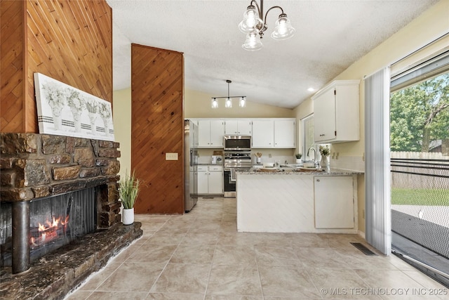 14127 E 24th Pl, Tulsa, OK 74134 - kitchen featuring vaulted ceiling, high end appliances, wood walls, a peninsula, and white cabinetry