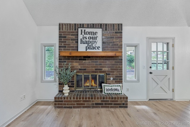 2244 W 45th St, Tulsa, OK 74107 - unfurnished living room with a textured ceiling, wood finished floors, lofted ceiling, healthy amount of natural light, and a fireplace