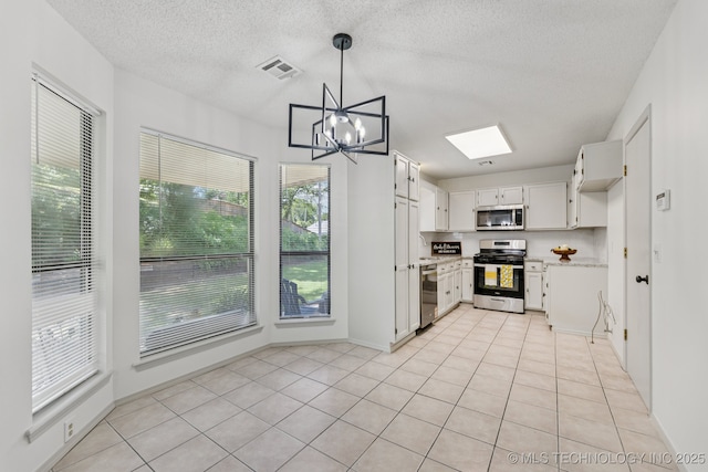 2244 W 45th St, Tulsa, OK 74107 - kitchen featuring appliances with stainless steel finishes, healthy amount of natural light, a chandelier, white cabinets, and a textured ceiling
