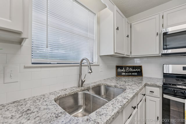 2244 W 45th St, Tulsa, OK 74107 - kitchen with appliances with stainless steel finishes, backsplash, white cabinets, a textured ceiling, and light stone counters