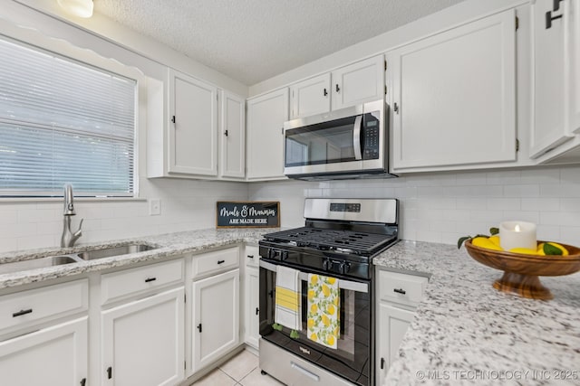 2244 W 45th St, Tulsa, OK 74107 - kitchen featuring stainless steel appliances, white cabinets, decorative backsplash, a textured ceiling, and light stone countertops