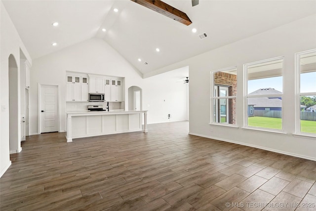 2916 S 8th St, Broken Arrow, OK 74012 - unfurnished living room featuring arched walkways, ceiling fan, high vaulted ceiling, dark wood-type flooring, and beam ceiling