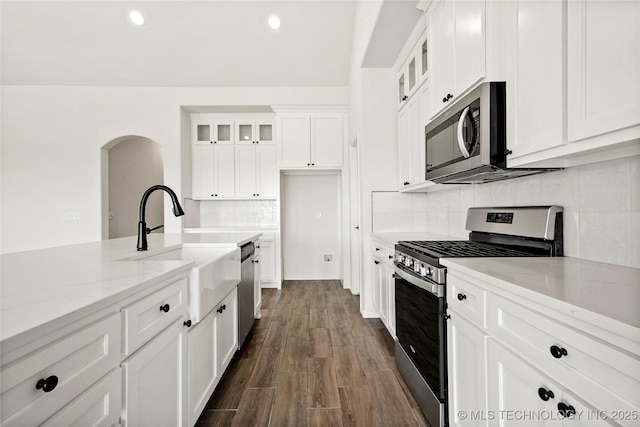 2916 S 8th St, Broken Arrow, OK 74012 - kitchen featuring stainless steel appliances, arched walkways, white cabinetry, backsplash, and glass insert cabinets