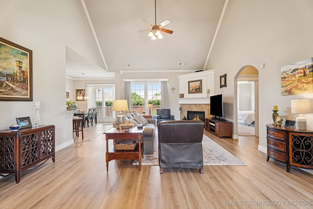 12432 S 101st E Ave, Bixby, OK 74008 - living area with high vaulted ceiling, ceiling fan, a tiled fireplace, light wood-style floors, and arched walkways