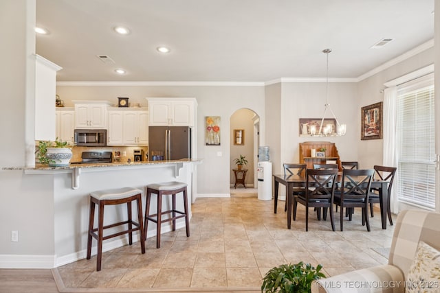 12432 S 101st E Ave, Bixby, OK 74008 - kitchen featuring stainless steel appliances, arched walkways, a kitchen bar, light stone countertops, and crown molding