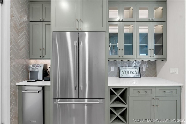 1207 N 71st Pl, Broken Arrow, OK 74014 - kitchen with high quality fridge, decorative backsplash, glass insert cabinets, gray cabinetry, and light stone counters