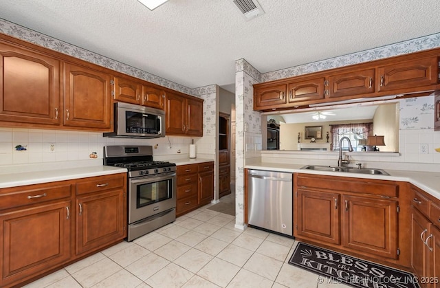 8318 S 84th E Ave, Tulsa, OK 74133 - kitchen with stainless steel appliances, light countertops, brown cabinets, wallpapered walls, and light tile patterned flooring