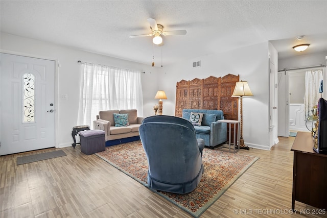 12750 E 23rd St, Tulsa, OK 74129 - living area with ceiling fan, a barn door, a textured ceiling, and wood finished floors