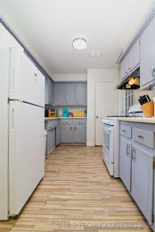 12750 E 23rd St, Tulsa, OK 74129 - kitchen featuring white appliances, gray cabinets, under cabinet range hood, and light wood finished floors