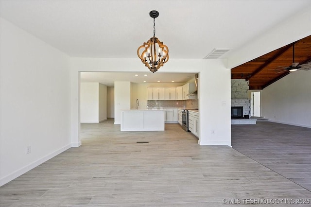 13973 S 237th E Ave, Coweta, OK 74429 - kitchen with open floor plan, a chandelier, stainless steel range with electric cooktop, a stone fireplace, and beam ceiling