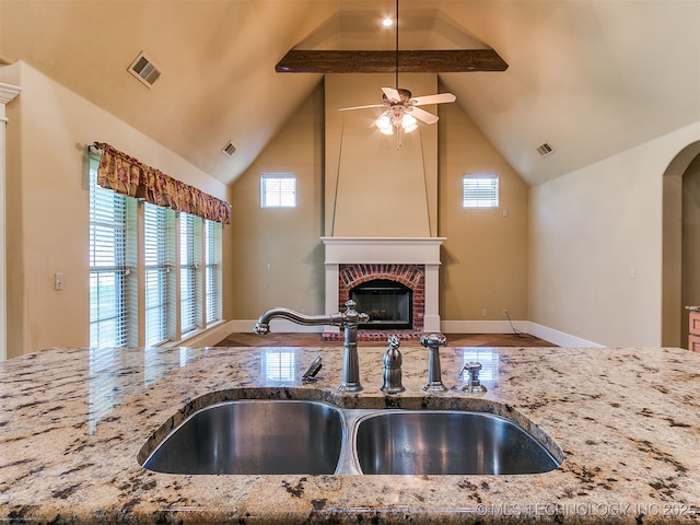 9314 S 76th E Ave, Tulsa, OK 74133 - kitchen with stone counters, ceiling fan, a fireplace, open floor plan, and arched walkways