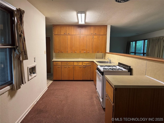 2306 Hill Dr, Bartlesville, OK 74006 - kitchen with white gas stove, light carpet, light countertops, brown cabinetry, and a textured ceiling