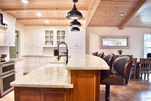 71279 S 270th Rd, Wagoner, OK 74467 - kitchen with a wood ceiling with exposed beams, double oven range, recessed lighting, white cabinetry, and a kitchen island with sink
