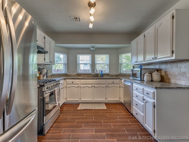 4004 S Sycamore Ave, Broken Arrow, OK 74011 - kitchen featuring appliances with stainless steel finishes, white cabinetry, tasteful backsplash, exhaust hood, and dark wood-style flooring