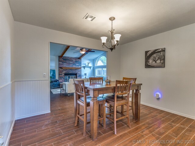 4004 S Sycamore Ave, Broken Arrow, OK 74011 - dining area with dark wood-type flooring, ceiling fan, a fireplace, a chandelier, and a wainscoted wall