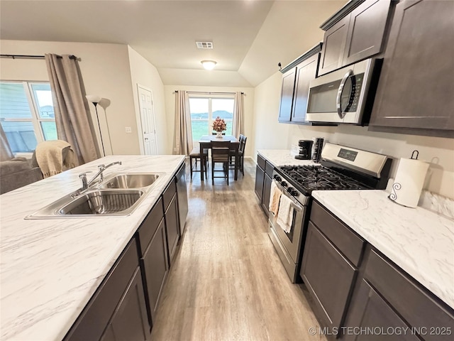 3907 S 150th E Ave, Tulsa, OK 74134 - kitchen featuring stainless steel appliances, light wood-type flooring, lofted ceiling, light stone counters, and dark brown cabinetry