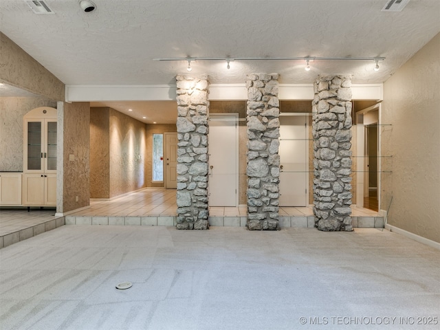 5704 E 65th St, Tulsa, OK 74136 - unfurnished living room featuring decorative columns, carpet, track lighting, and a textured ceiling