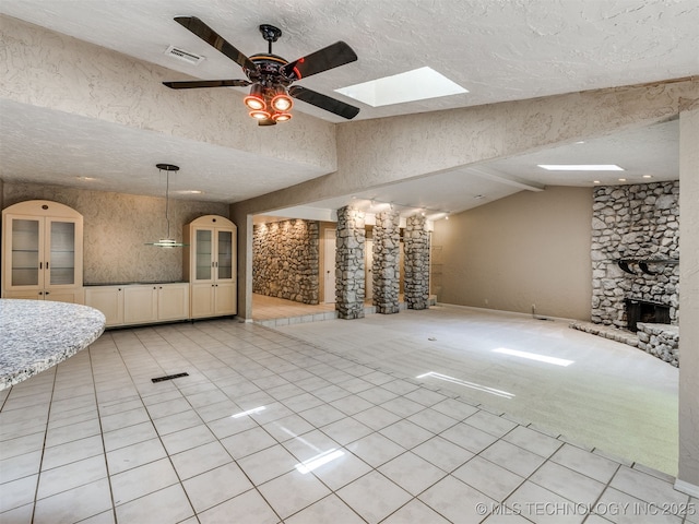5704 E 65th St, Tulsa, OK 74136 - unfurnished living room featuring a ceiling fan, light tile patterned flooring, vaulted ceiling, a textured ceiling, and a stone fireplace