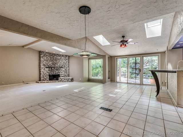 5704 E 65th St, Tulsa, OK 74136 - unfurnished living room featuring a skylight, lofted ceiling, light tile patterned flooring, a fireplace, and a ceiling fan