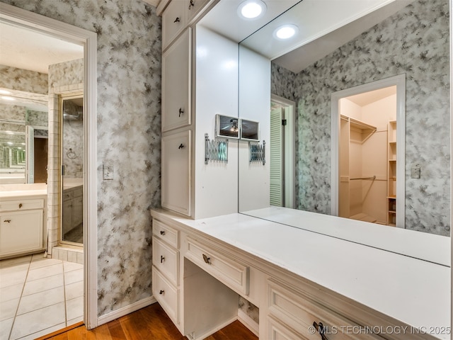 5704 E 65th St, Tulsa, OK 74136 - bathroom with wood finished floors, a shower stall, a walk in closet, vanity, and wallpapered walls