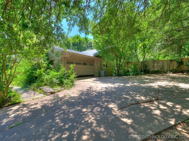 5704 E 65th St, Tulsa, OK 74136 - view of home's exterior featuring stone siding, driveway, and a garage