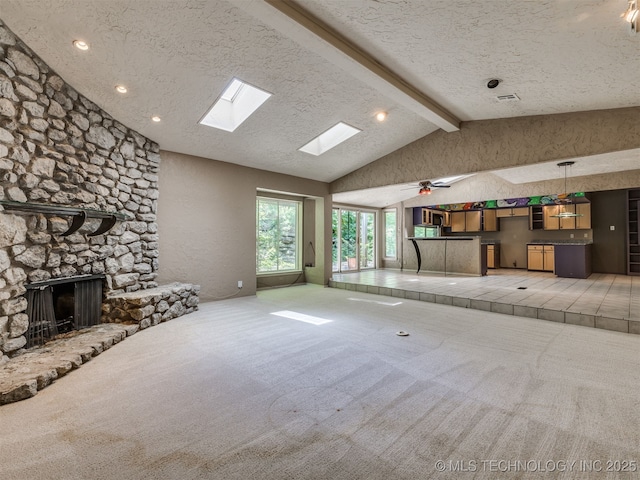 5704 E 65th St, Tulsa, OK 74136 - unfurnished living room featuring light carpet, a textured ceiling, a skylight, a fireplace, and ceiling fan