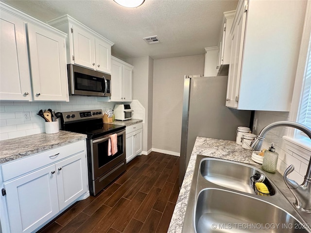 1404 Compelube Rd, Mcalester, OK 74501 - kitchen featuring stainless steel appliances, decorative backsplash, dark wood-type flooring, white cabinets, and a textured ceiling