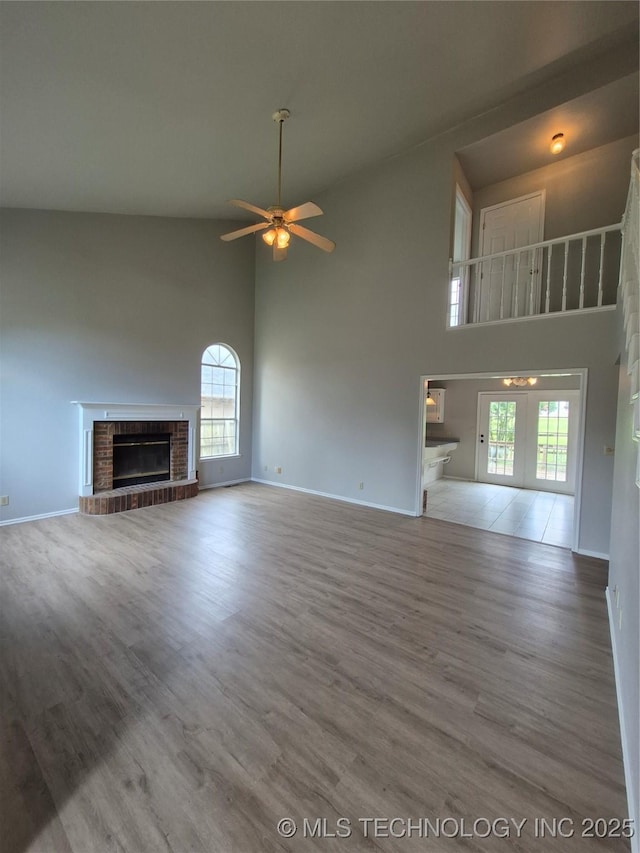 2200 SW Wolf Run Ct, Claremore, OK 74019 - unfurnished living room featuring a towering ceiling, a fireplace, ceiling fan, and wood finished floors