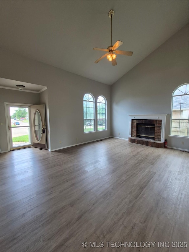 2200 SW Wolf Run Ct, Claremore, OK 74019 - unfurnished living room featuring a ceiling fan, healthy amount of natural light, wood finished floors, high vaulted ceiling, and a brick fireplace