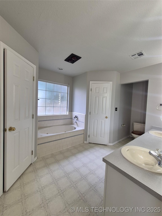 2200 SW Wolf Run Ct, Claremore, OK 74019 - bathroom with a bath, double vanity, tile patterned floors, and a textured ceiling