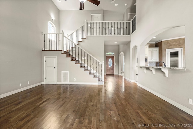 1317 W Dover St, Broken Arrow, OK 74012 - foyer featuring ceiling fan, a towering ceiling, dark wood-type flooring, stairway, and arched walkways