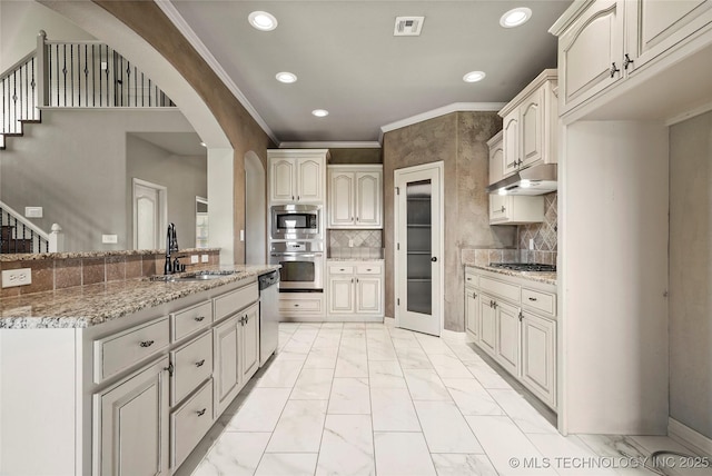 1317 W Dover St, Broken Arrow, OK 74012 - kitchen featuring appliances with stainless steel finishes, light marble finish flooring, under cabinet range hood, recessed lighting, and arched walkways