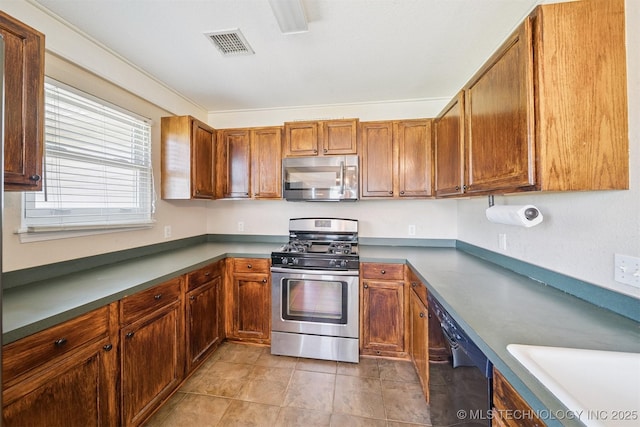11691 N 193rd E Ave, Collinsville, OK 74021 - kitchen featuring stainless steel appliances, light tile patterned flooring, and brown cabinetry