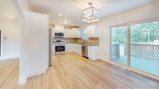 403 N Vine Ave, Cleveland, OK 74020 - kitchen featuring stainless steel appliances, decorative backsplash, light wood-type flooring, white cabinetry, and pendant lighting