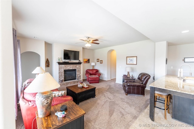11105 N 145th E Pl, Owasso, OK 74055 - carpeted living room featuring arched walkways, a ceiling fan, and a fireplace