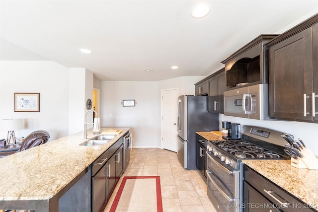 11105 N 145th E Pl, Owasso, OK 74055 - kitchen with stainless steel appliances, dark brown cabinets, a center island with sink, light stone counters, and recessed lighting
