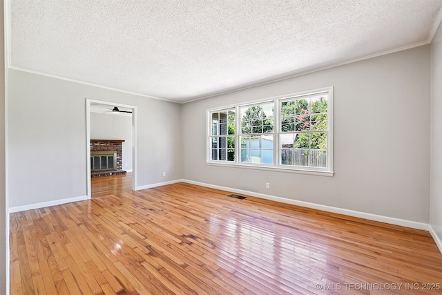 4643 E 59th St, Tulsa, OK 74135 - spare room with light wood-type flooring, a textured ceiling, crown molding, a fireplace, and ceiling fan