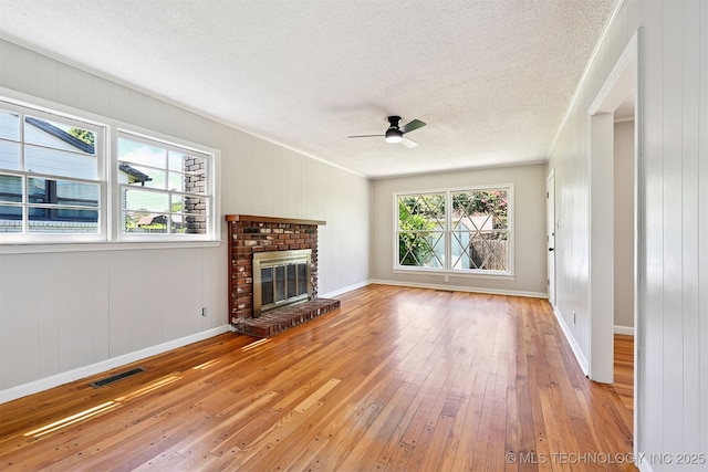 4643 E 59th St, Tulsa, OK 74135 - unfurnished living room featuring light wood-style floors, a textured ceiling, a ceiling fan, a brick fireplace, and ornamental molding
