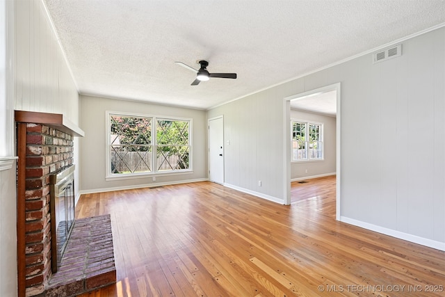 4643 E 59th St, Tulsa, OK 74135 - unfurnished living room featuring ceiling fan, light wood-style floors, a textured ceiling, a fireplace, and ornamental molding